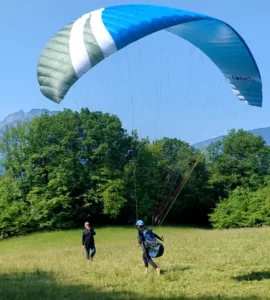 Un moniteur guide un élève au sol pour apprendre à gonfler la voile lors d'un stage de parapente à Annecy.